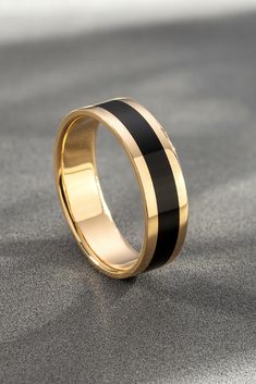 a gold ring with black stripes on the outside and inside, sitting on a gray surface