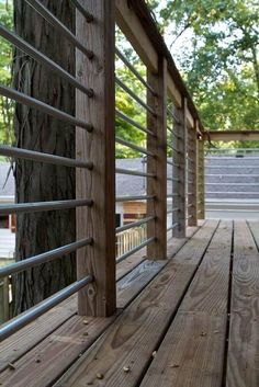 a wooden deck with metal railings and trees in the background