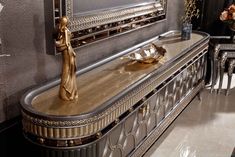 a gold plate on top of a black and silver dresser in a room with mirrors