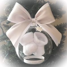 a baby's first christmas ornament hanging on a tree with a bow