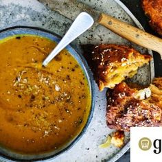 a bowl of soup and some bread on a plate