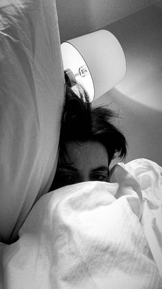 a person laying in bed under a pillow with a hair dryer on top of their head