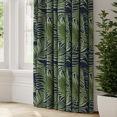 a green and blue curtain hanging in front of a window next to a potted plant