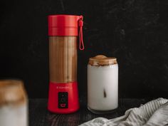 a red blender sitting next to a cup on top of a table