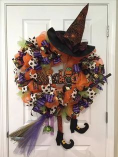 a halloween wreath on the front door decorated with witch hats, pumpkins and decorations