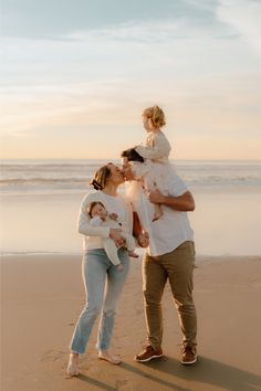 a man, woman and child standing on the beach with their arms around each other