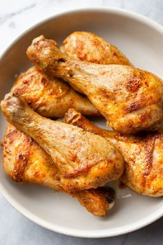 chicken wings in a white bowl on a marble counter top, ready to be cooked