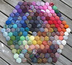 multicolored balls of yarn laid out on a wooden surface in the shape of a hexagon