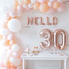 a balloon arch with the number 30 on it in front of a white brick wall