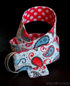 a red and white polka dot dog collar with a blue paisley bow tie on it