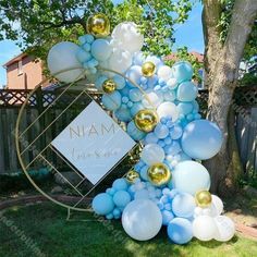 a bunch of balloons that are in the grass next to a sign and some trees