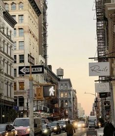 cars are driving down the street in front of tall buildings with signs on each side