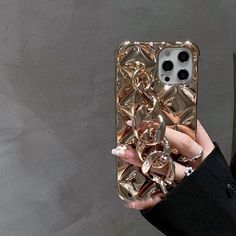 a woman is holding up her phone case with gold chains on the front and sides