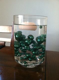 a glass filled with green balls on top of a wooden table