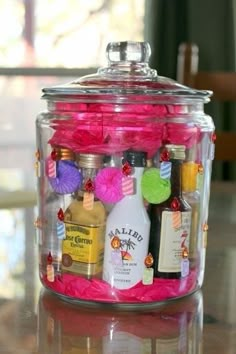 a glass jar filled with liquor bottles on top of a table