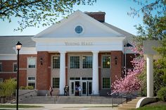 the young hall building is surrounded by flowering trees and steps leading up to it's entrance