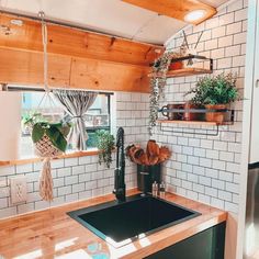 a kitchen with white brick walls and wooden floors, an open window above the sink