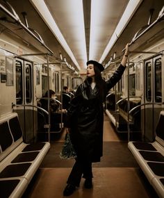 a woman standing on a subway train with her arms in the air and looking up