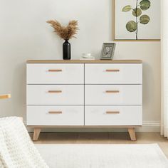 a white dresser sitting in a bedroom next to a window with plants on top of it