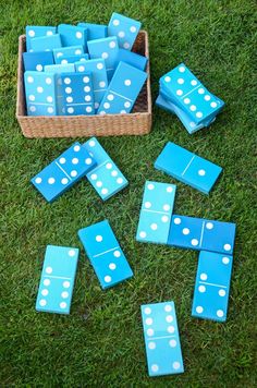 blue and white dominos laid out on the grass in front of a basket full of them