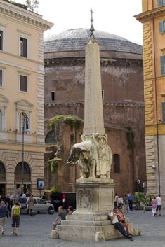 people sitting on the ground near a statue in front of a building with a dome