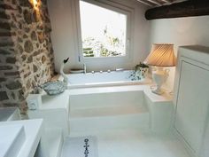 a bathroom with stone walls and flooring next to a bathtub in the corner