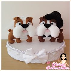 two stuffed dogs sitting on top of a cake