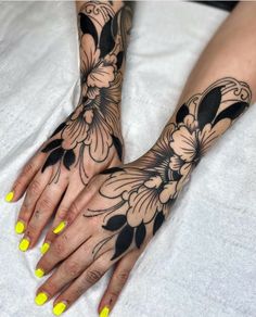 a woman's hands with yellow fingernails and tattoos on her left hand, holding onto the