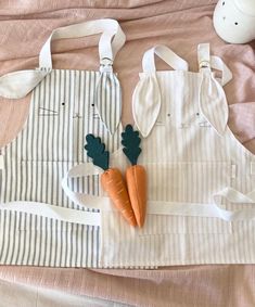 two carrots are sitting on a white apron and some other things to make it look like they have been made out of fabric