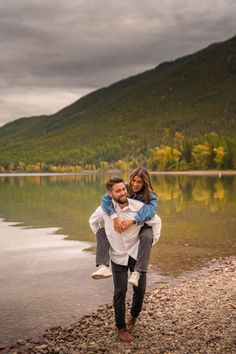 a man carrying a woman on his back by the water