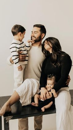 a man, woman and two children sitting on a bench with food in their mouth