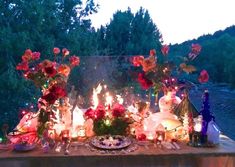 a table topped with lots of candles and flowers on top of a table covered in wine bottles