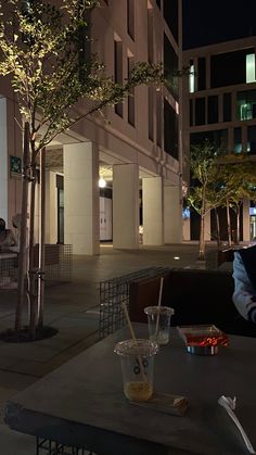 a man sitting at a table in front of a tall building