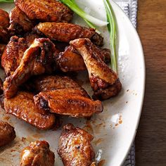 a white plate topped with chicken wings next to celery sticks and an onion wedge