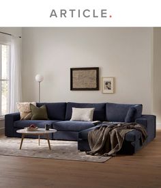 a living room with a blue couch and white curtains on the window sill next to a coffee table