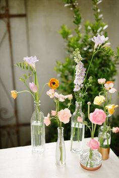 several vases with flowers in them sitting on a table