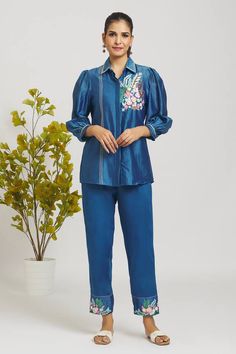 Peacock blue chanderi shirt with placed floral crochet embroidery. Comes with matching pant.
Components: 2
Pattern: Embroidered
Type Of Work: Crochet
Neckline: Shirt Collar
Sleeve Type: Full
Fabric: Shirt: Chanderi, Pant: Italian Cotton, Lining: Mulmul
Color: Blue
Other Details: 
Attached lining
Weight: 250 grms
Closure: Shirt: Front button
Occasion: Party,Work - Aza Fashions Blue Floral Embroidered Pant Set For Spring, Festive Blue Embroidered Pant Set, Blue Floral Embroidery Pant Set For Spring, Festive Embroidered Blue Pant Set, Traditional Blue Pant Set With Floral Embroidery, Blue Pant Set With Resham Embroidery, Festive Blue Long Sleeve Pant Set, Blue Resham Embroidery Pant Set For Diwali, Blue Embroidered Pant Set For Diwali