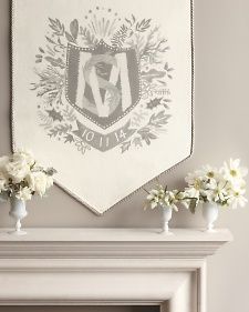 two vases with white flowers are sitting on a mantle in front of a wall hanging