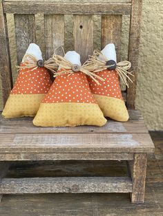 two orange and white pillows sitting on top of a wooden chair next to each other