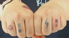 two fingers with different tattoos on them