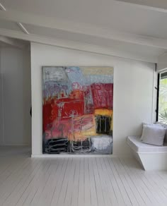 a large painting is hanging on the wall in a white room with wood flooring