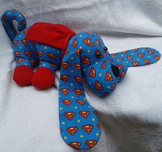 a blue stuffed dog with superman print on it's face and neck laying down