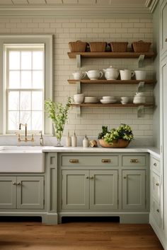 a kitchen filled with lots of counter space next to a white sink and wooden shelves