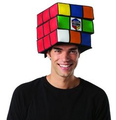 a man wearing a rubik cube hat on top of his head and smiling at the camera