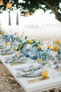 a long table set with blue and white plates, silverware and flowers on it