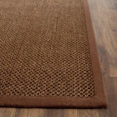 a brown area rug on the floor with wood floors in the background and an empty chair at the far end