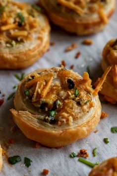 several small pastries with toppings on top of paper