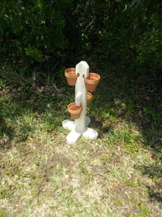 a white statue with two clay pots on it's back legs in the grass