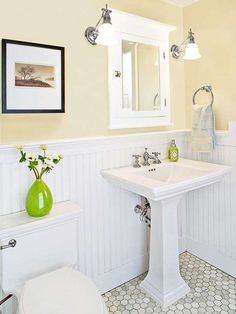 a white bathroom with green vase on the sink