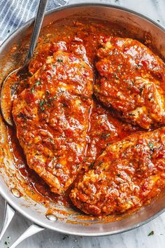 two pieces of meat covered in marinara sauce in a skillet